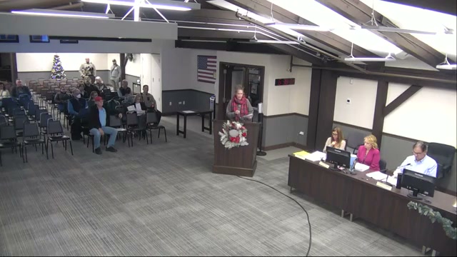 Heidi Pacella at the podium in the Homer Glen Village Board room, December 10, 2025, notes in hand.