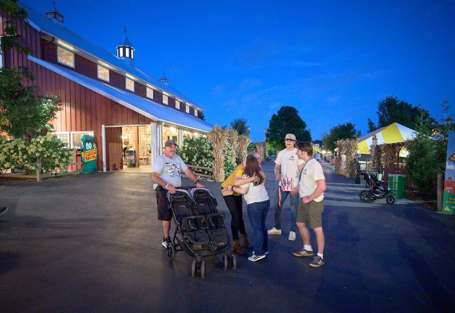 Blue hour outside Bengtson's red barn: Heidi hugs a supporter while volunteers and a neighbor with a stroller look on.